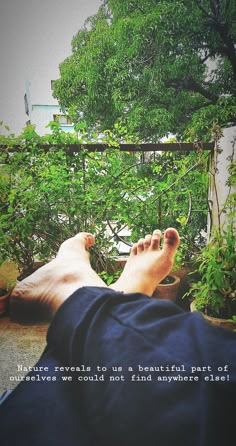 a person laying down with their feet propped up on the ground next to some plants