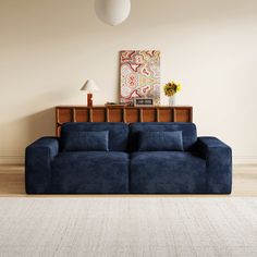 a blue couch sitting on top of a hard wood floor next to a white rug