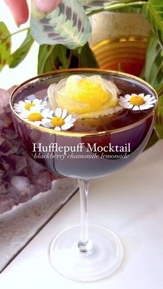 a glass with some food in it sitting on a table next to rocks and flowers