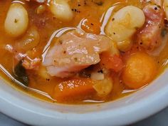 a white bowl filled with soup and meat on top of a blue cloth tablecloth