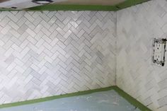 a bathroom with white tiles and green trim on the walls, in need of remodeling