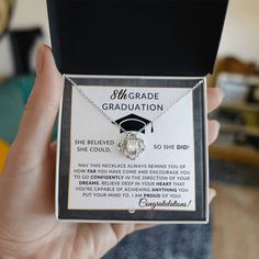 a person holding up a graduation necklace in a box with an information card attached to it