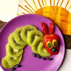 a purple plate topped with sliced kiwis and strawberries on top of it