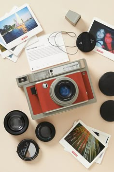 an old fashioned camera surrounded by other items on a beige surface with photos and magnets