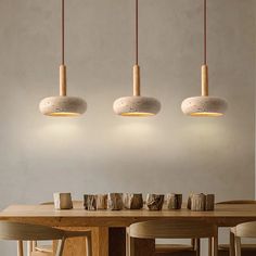 three lights hanging over a wooden table with chairs