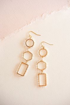 These stunning earrings boast a captivating geometric design accented with intricate beads, exuding a luxurious charm that effortlessly elevates any look. Crafted from gleaming gold-toned metal, they are both lightweight and comfortable, ensuring all-day wearability with a touch of glamour. Whether paired with casual attire or formal wear, the Caroline Geometric Dangle Earrings are the perfect choice to make a chic statement. Chic Gold Beaded Dangle Earrings, Chic Gold Dangle Beaded Earrings, Elegant Gold Hoop Earrings With Faceted Beads, Gold Beaded Geometric Earrings, Gold Geometric Beaded Earrings As A Gift, Gold Geometric Beaded Earrings For Gift, Gold Geometric Beaded Earrings, Geometric Beaded Gold Earrings, Gold Beaded Geometric Jewelry