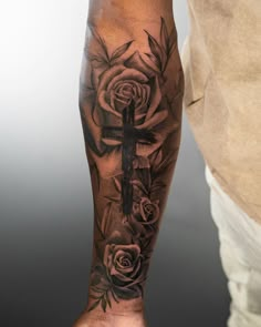 a man with a cross and roses tattoo on his arm