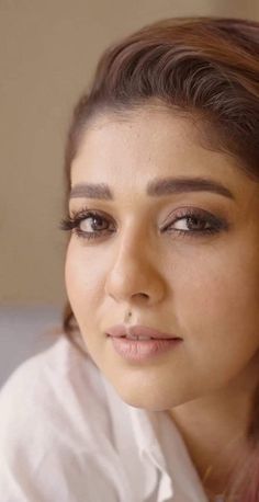 a close up of a person wearing a white shirt and eyeliner with long hair