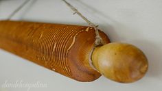 a wooden object hanging on the wall with string and wood ball attached to it's side