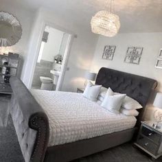 a bedroom with a large bed and chandelier hanging from the ceiling