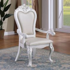 a white chair sitting on top of a rug in a living room next to a potted plant