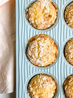 a muffin tin filled with baked goods on top of a blue table cloth next to a white towel