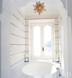 a bath room with a white tub and a star shaped chandelier above it