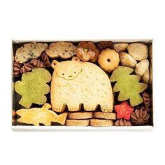 an assortment of cookies in a box with a bear and leaves on the top one