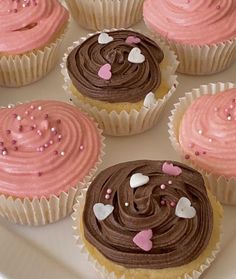 cupcakes with pink and chocolate frosting on a white plate, decorated with hearts