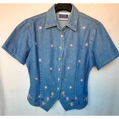 Vintage Bill Blass Floral Embroidered Denim Button Up Shirt Women New Casual Western But Feminine Look Floral Embroidered Front, Solid Denim Back Panel Seven (7) Buttons, Short Sleeves Generous But Fitted Design New, Unused And Unworn Condition Circa 1990s Size: Small Color: Denim Blue With Multicolor Embroidery Fabric: Cotton Bust: 40 In Length: 21 In Shoulder-To-Shoulder: 17 In Sleeve Length: 8 In Made In Hong Kong Spring Medium Wash Denim Shirt, Spring Medium Wash Shirt With Buttons, Spring Denim Shirt With Snap Buttons, Medium Wash Shirt With Buttons For Spring, Fitted Denim Summer Shirt, Fitted Embroidered Medium Wash Tops, Fitted Denim Blue Tops With Floral Embroidery, Spring Denim Blue Tops With Button Closure, Spring Denim Tops With Button Closure