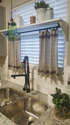 a kitchen sink under a window next to a potted plant