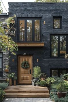 a black brick house with wooden front door and steps leading up to the entryway