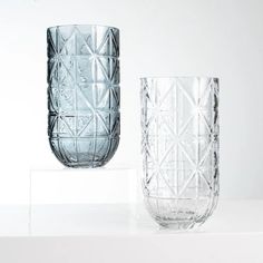 two clear glass vases sitting on top of a white table next to each other