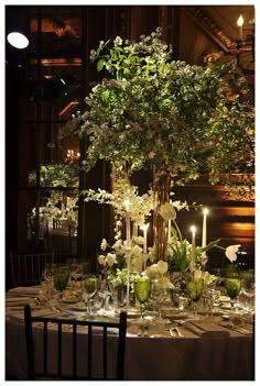 the table is set with flowers and candles for an elegant wedding reception at night time