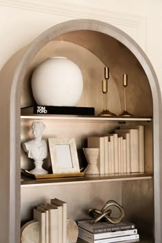 a book shelf with books and vases on it's shelves in a room