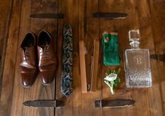 an assortment of men's accessories laid out on a wooden floor next to a bottle and knife