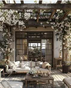 an outdoor living room with white furniture and flowers on the ceiling, along with potted plants