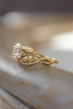 a close up of a gold ring with a diamond in it's center on top of a table