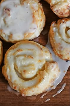 cinnamon rolls with icing sitting on top of a wooden table