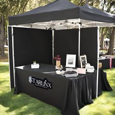 a black tent set up on the grass with pictures and other items sitting under it