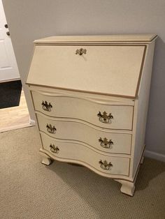 a white dresser sitting on top of a carpeted floor next to a wall and door