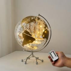 a person holding a remote control in front of a small globe with lights on it