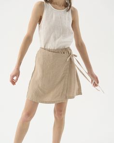 "Our take on a leisure tennis skirt - linen shorts with a wrap front, also known as a skort. The perfect blend of grace and comfort. Offered in medium-weight and exclusive linen. STYLE DETAILS * Regular fit * High rise * Elasticated waist * Wrap ties at the front * Mini length * Made from medium weight and exclusive linen SIZES & COLORS IN THE PICTURES * Model is wearing size M in Beige (medium) linen Model's height - 175 cm (5'9\"), bust 80 cm (31.5\"), waist 59 cm (23.2\"), hips 89 cm (35\"). Short Cotton Skirt For Summer, Cotton Mini Skirt For Summer, Short Cotton Summer Skirt, Cotton Mini Skort For Summer, Summer Cotton Mini Skort, Chic Drawstring Mini Skirt For Summer, Chic Summer Mini Skirt With Drawstring, Casual Tie Waist Mini Wrap Skirt, Linen Drawstring Shorts For Day Out