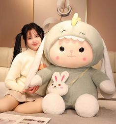 a woman sitting on the floor next to a large stuffed animal with bunny ears and tail