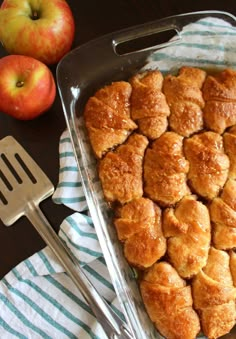 a pan filled with pastries next to an apple