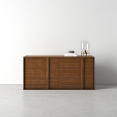 an empty room with a sideboard and vase on it's stand, in front of a white wall