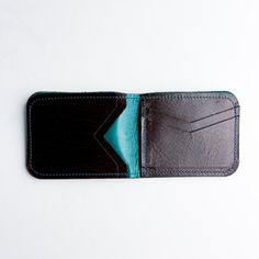 Our perfect Everyday wallet --- updated design with a few extra pockets. Carry cash + cards effortlessly with our very slim, single fold wallet. Available in Black + Rocky, Turquoise + Rocky, and Rocky + Black. Turquoise Rectangular Wallet For Everyday Use, Black Textured Leather Wallet, Rectangular Travel Wallets With Silver-tone Hardware, Blue Rectangular Wallet With Zipper Pocket, Black Leather Wallet Hand-stitched, Bison Leather, Fold Wallet, Men's Collection, High Quality Leather