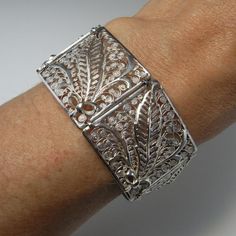 Here is an exceptional Art Nouveau completely handmade silver filigree bracelet circa 1890. The workmanship here is reminiscent of 18th century filigree in the quality and intricacy of this amazing piece. Each panel is entirely made by hand with silver wire twisted and wound into a fern and frond design each bouquet tied with a feminine bow. Amazingly each panel is not flat but the silver lace design is raised in relief with the central fern frond sitting higher to the rest of the panel. When th Elegant Luxury Antique Silver Cuff Bracelet, Elegant Engraved Ceremonial Cuff Bracelet, Elegant Ceremonial Engraved Cuff Bracelet, Elegant Engraved Cuff Bracelet For Ceremonial Occasions, Wedding Filigree Bangle Bracelets, Luxury Silver Engraved Filigree Ring, Luxury Engraved Silver Filigree Ring, Elegant Engraved Sterling Silver Bracelet In White Gold, Victorian Cuff Bracelet With Intricate Design For Ceremonial