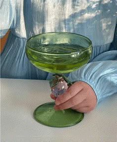 a person is holding a green glass bowl with something in it that looks like an object