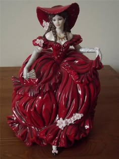 a red ceramic figurine sitting on top of a wooden table