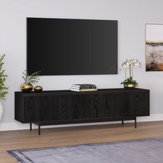 a large flat screen tv mounted to the side of a wall next to a plant