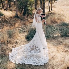 a woman in a white wedding dress standing in the woods with her veil pulled back