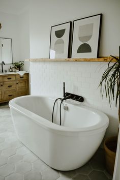 a large white bath tub sitting in a bathroom next to a wooden dresser and mirror