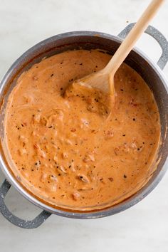 a wooden spoon in a pot filled with sauce