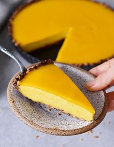 a person holding a slice of cheesecake on a plate