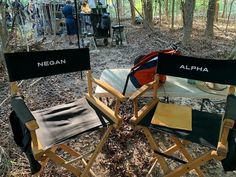 two folding chairs sitting in the woods next to each other with their names on them