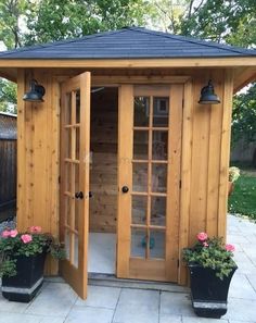 an outdoor sauna with two potted plants in it and one door open to the outside