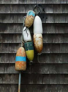 an assortment of buoys are hanging on the side of a wooden building with a metal pole