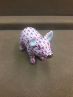 a pink and white pig figurine sitting on top of a brown countertop