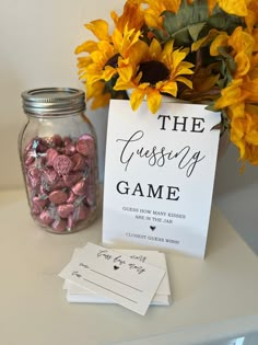 a vase with sunflowers and candy in it next to a sign that says the guess game